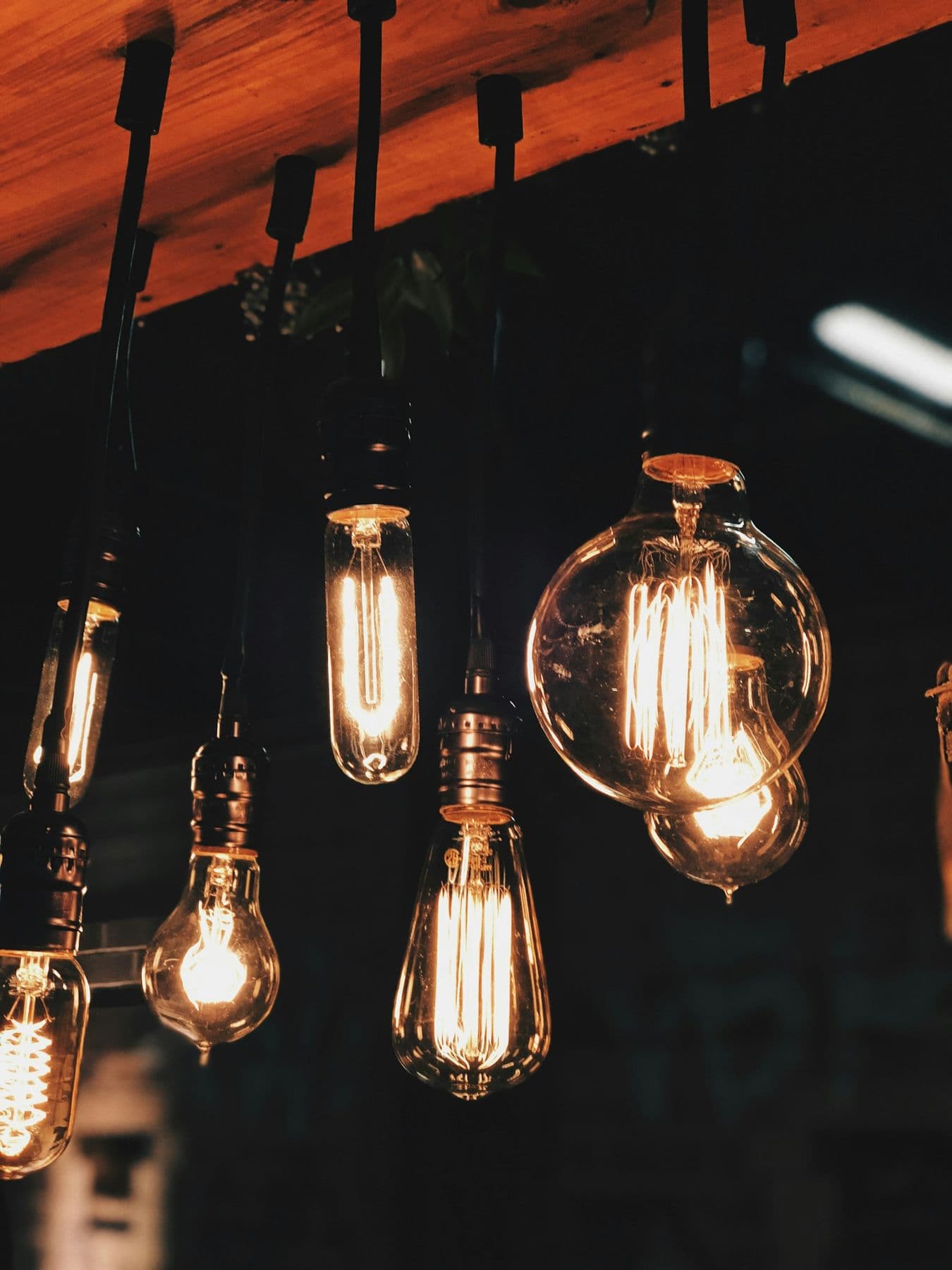 Warm Edison light bulbs glowing against a dark ceiling.